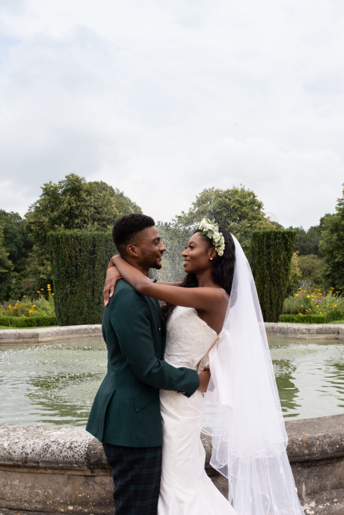 multicultural bride and groom standing in front of a fountain